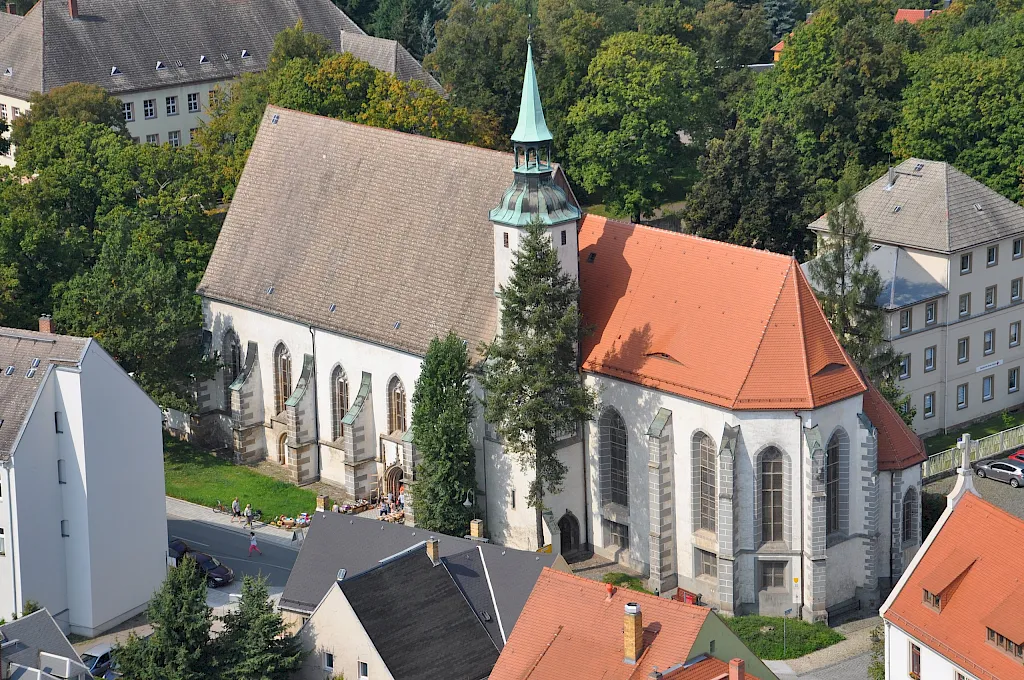 Luftbild der Klosterkirche Oschatz mit rotem Ziegeldach und grüner Turmhaube zwischen den Dächern der Altstadt