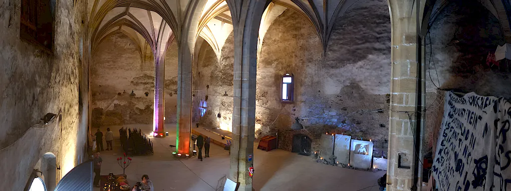 Panorama des Kirchenschiffs mit Gewölbe, Pfeilern und farbig angestrahlten Steinwänden
