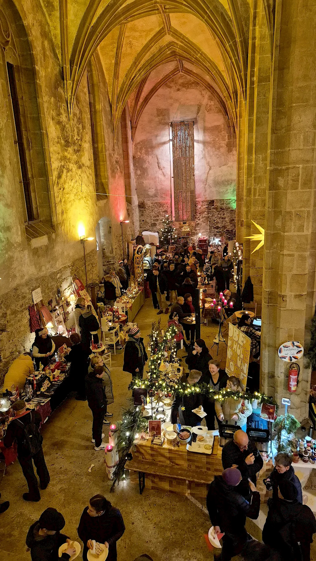 Blick von oben in das Kirchenschiff während des KlosterAdvents: Stände, Lichterketten und Besucher unter dem Gewölbe